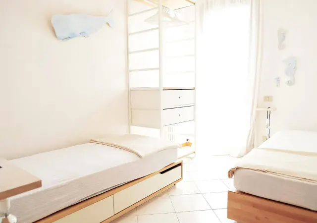BookNoFees: Ferienwohnung in Cavallino-Treporti, Italien – Zwei Betten in einem Schlafzimmer mit weissen Wänden im „Sunny Apartment On The Sea“ in Cavallino-Treporti