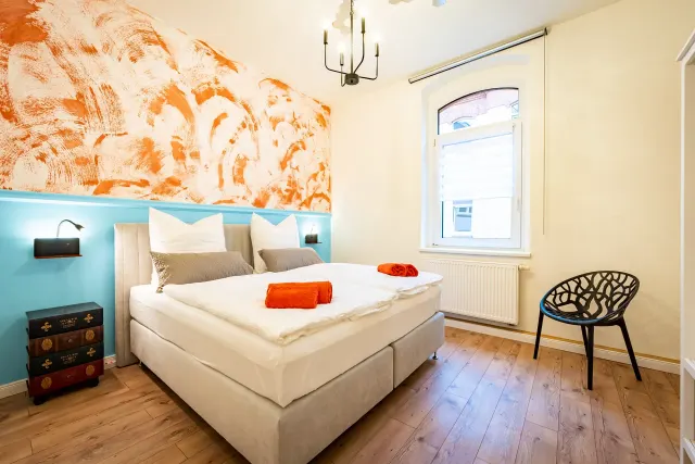 BookNoFees : location de vacances à Magdeburg, Allemagne – Chambre avec un lit double, un papier peint orange et une chaise noire