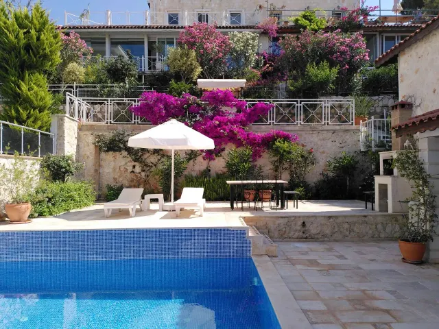 BookNoFees: casa vacanza a Kalkan, Kas, Antalya, Antalya, Turchia – Terrazza con piscina, sedie a sdraio, ombrellone e bouganville in fiore sui muri in pietra