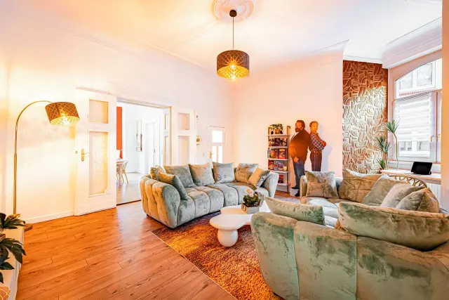 BookNoFees: casa vacanza a Magdeburg, Germania – Soggiorno con divani verdi dalla linea sinuosa, carta da parati a motivi e pavimento in legno