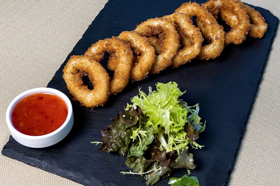 Photo d’illustration : Anneaux de calamars frits accompagnés d'une salade et d'une sauce pour tremper