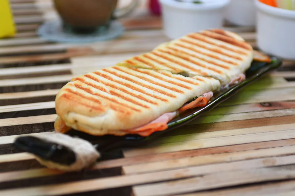 Beispielfoto: Ein geröstetes Panini mit Grillstreifen auf einem dunklen Teller