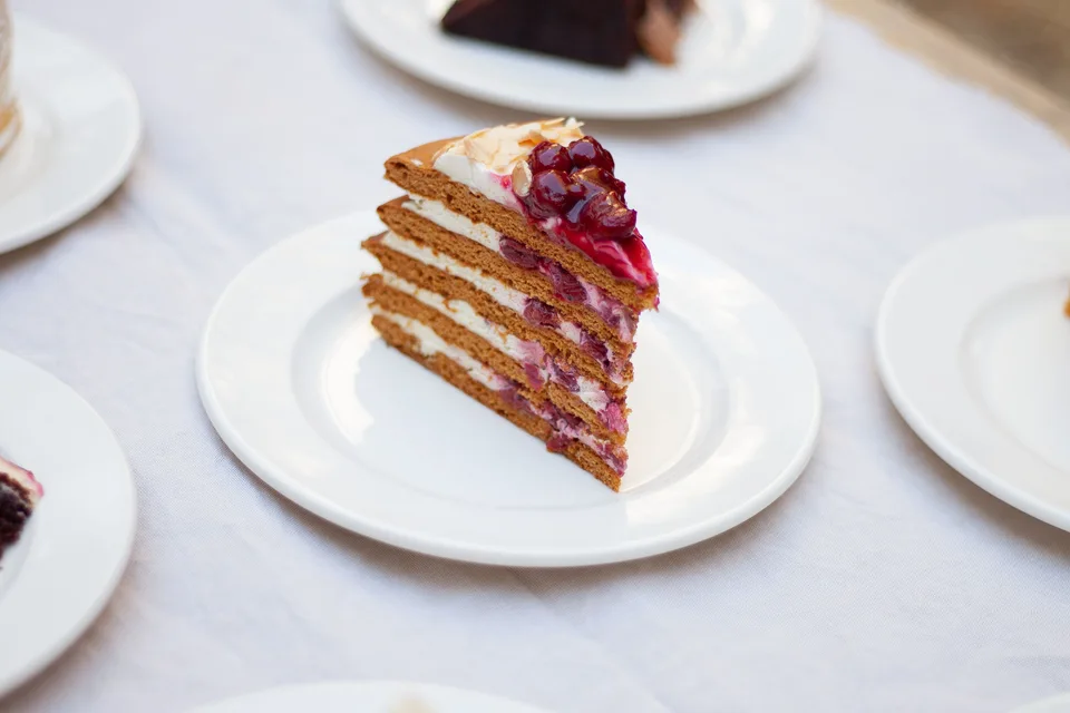 Beispielfoto: Ein Stück Schichtkuchen mit Beeren als Garnitur auf einem weissen Teller