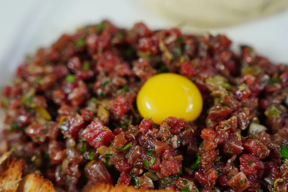 BookNoFees: Foto di esempio: Bistecca alla tartara guarnita con tuorlo d’uovo e servita con pane tostato